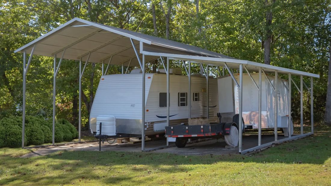 Tall metal carport covering a travel trailer and a utility trailer