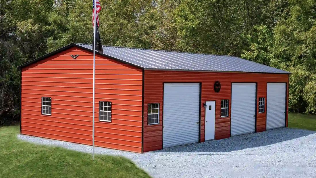 Red metal building with three roll up doors and windows