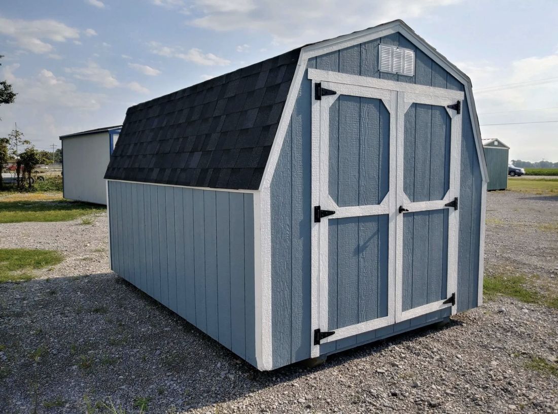 Blue barn style shed with white trim and a shingle roof